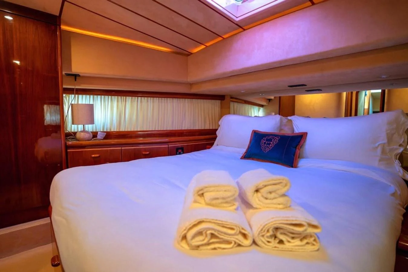 The stateroom features a plush bed with neatly arranged towels and warm ambient lighting. aboard FERRETTI 70 Yacht for Sale