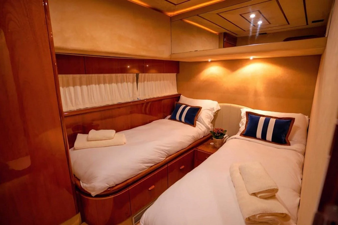 The twin stateroom offers cozy and elegant accommodations with warm lighting and plush bedding. aboard FERRETTI 70 Yacht for Sale