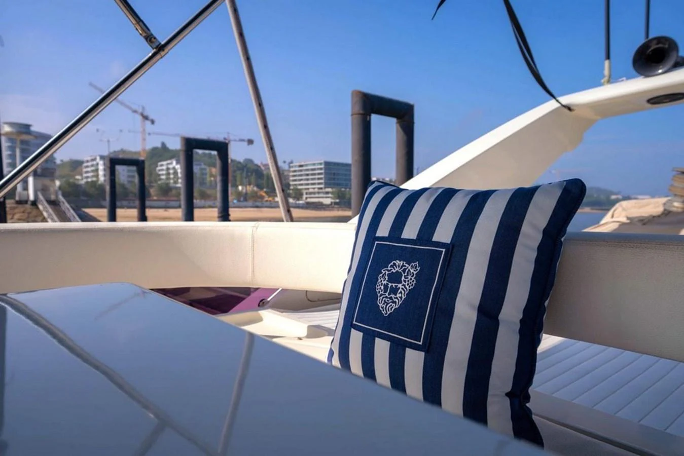 A close-up view of a stylish striped cushion on a yacht's seating area, with a serene waterfront backdrop. aboard FERRETTI 70 Yacht for Sale