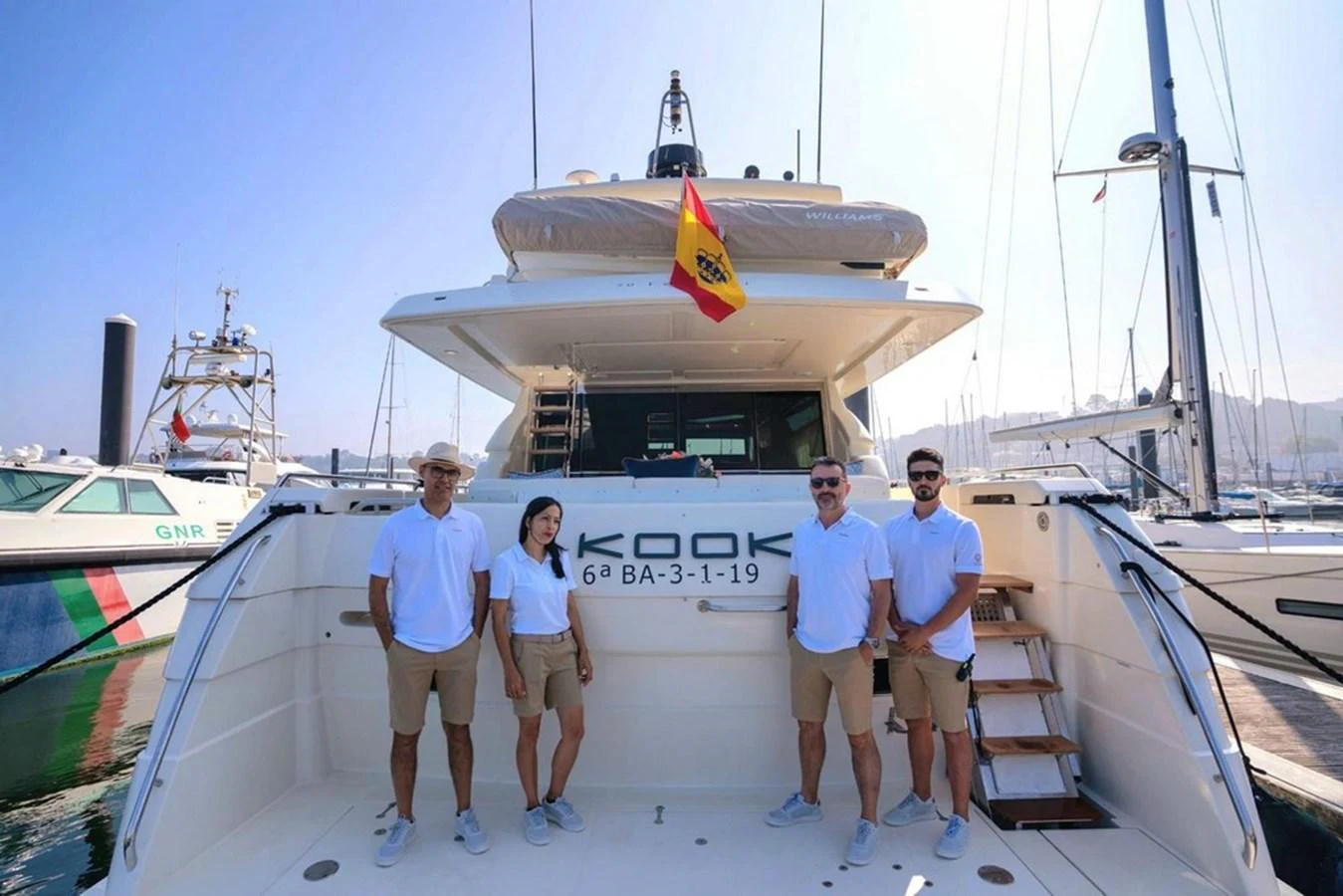 The crew stands proudly at the stern of the yacht, ready to welcome guests aboard. aboard FERRETTI 70 Yacht for Sale