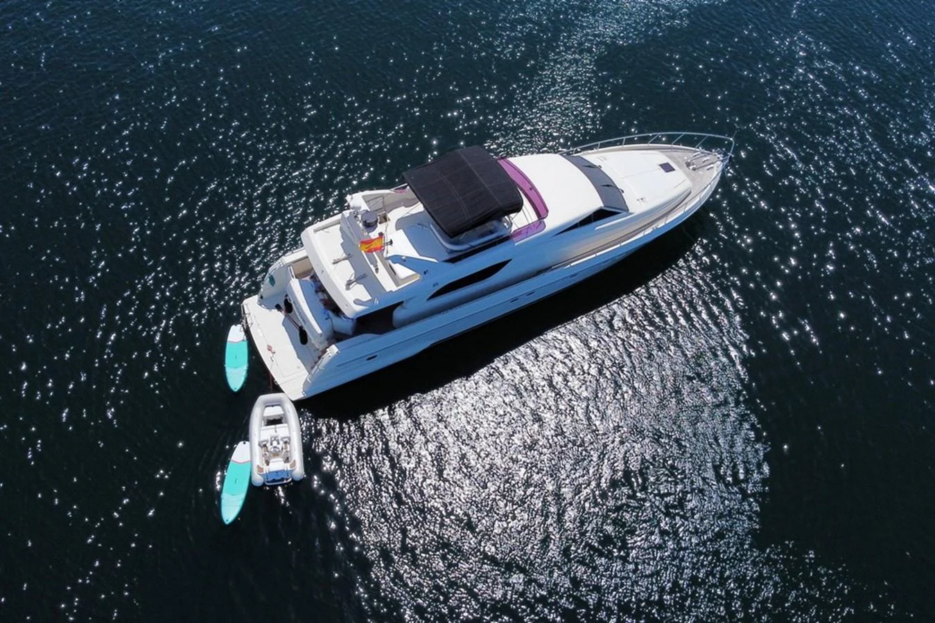 A sleek yacht glides gracefully on the water, accompanied by a tender and paddleboards. aboard FERRETTI 70 Yacht for Sale