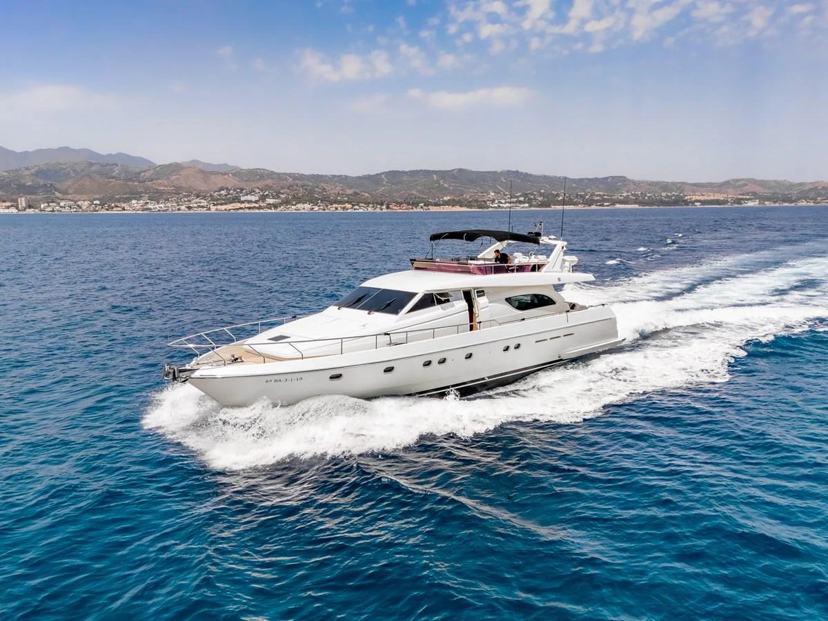 A sleek yacht cruises through clear blue waters with a scenic coastline in the background. aboard FERRETTI 70 Yacht for Sale