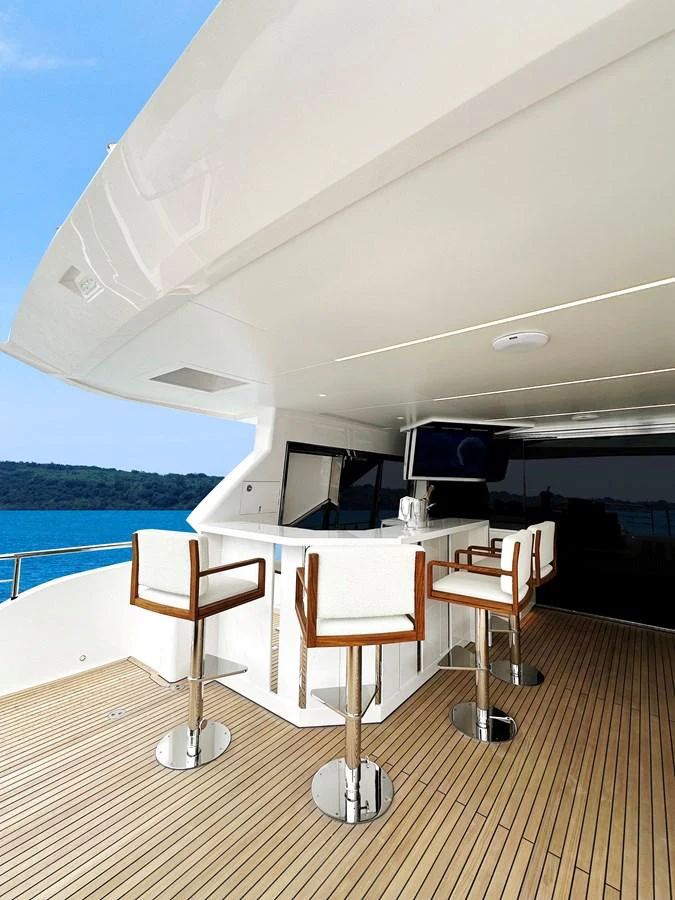 The aft deck features a stylish bar area with modern stools and a serene ocean view. aboard HORIZON FD90 Yacht for Sale