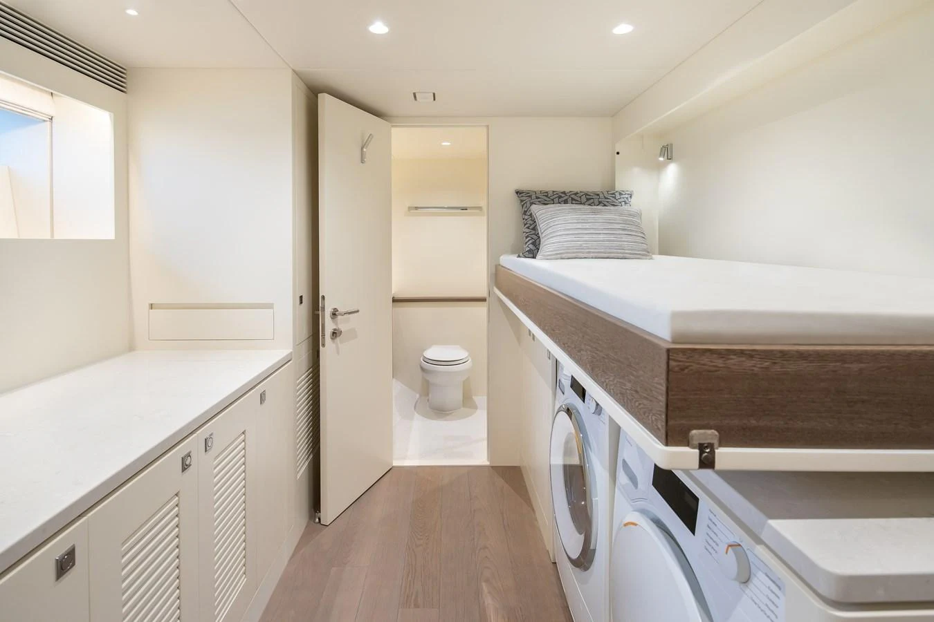 The crew quarters feature a compact yet functional layout with a bed, washing machine, and access to a private bathroom. aboard HORIZON FD90 Yacht for Sale