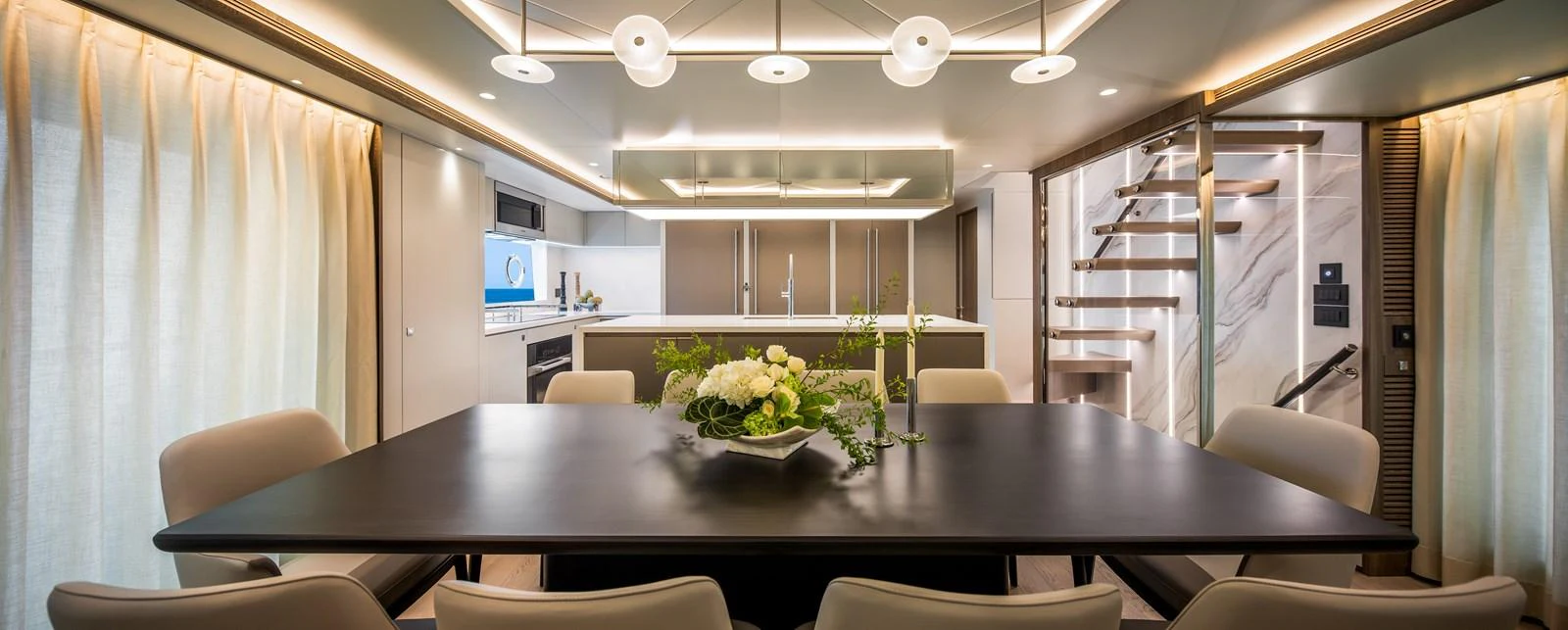 The yacht's dining area features a sleek table with comfortable seating and modern lighting. aboard HORIZON FD90 Yacht for Sale