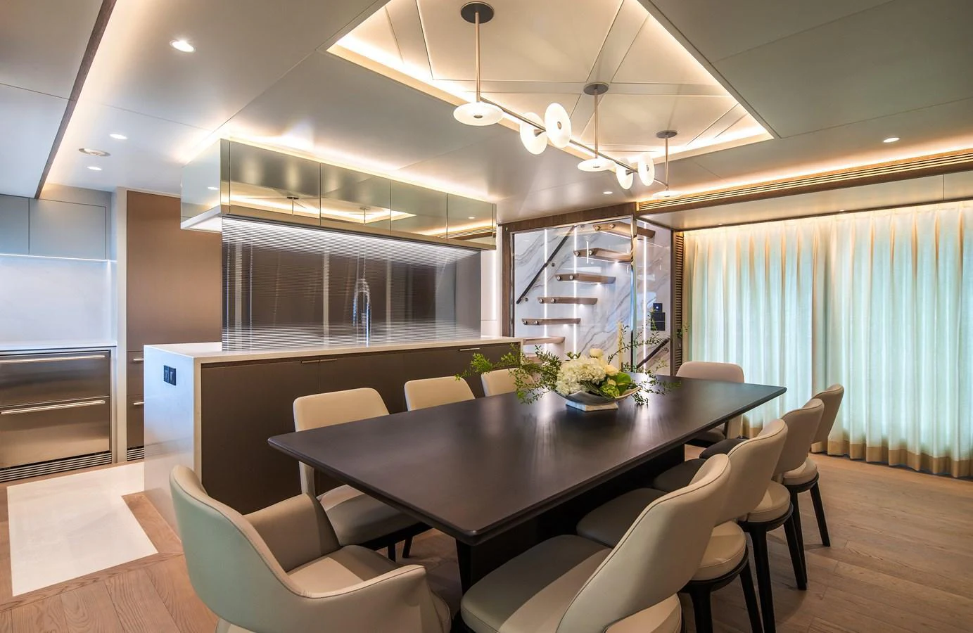 The yacht's dining area features a sleek table with plush seating, modern lighting, and elegant decor. aboard HORIZON FD90 Yacht for Sale