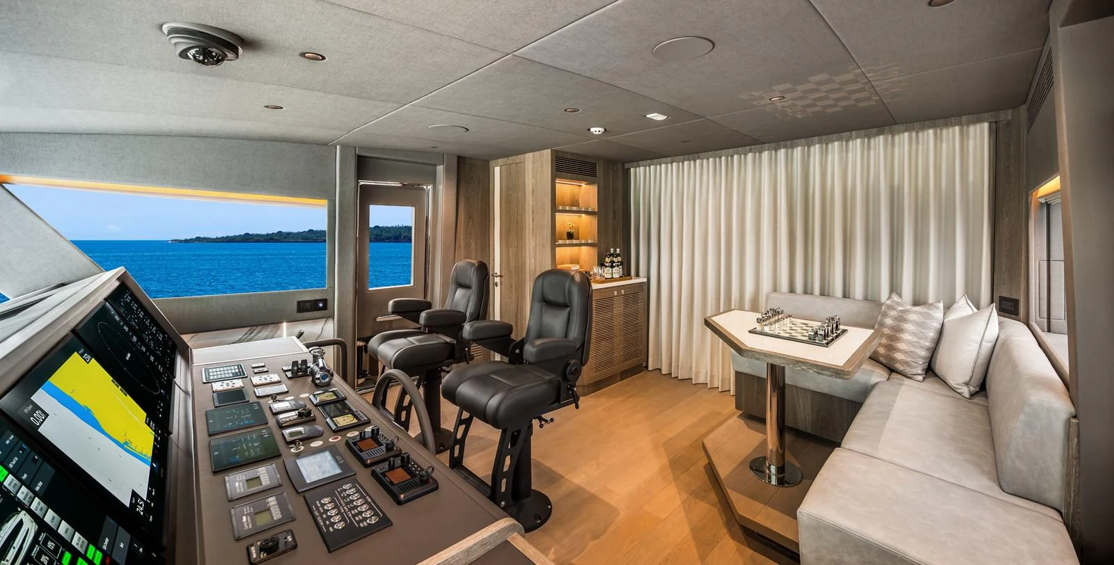 The helm area features state-of-the-art navigation equipment and a comfortable seating arrangement with a scenic view. aboard HORIZON FD90 Yacht for Sale