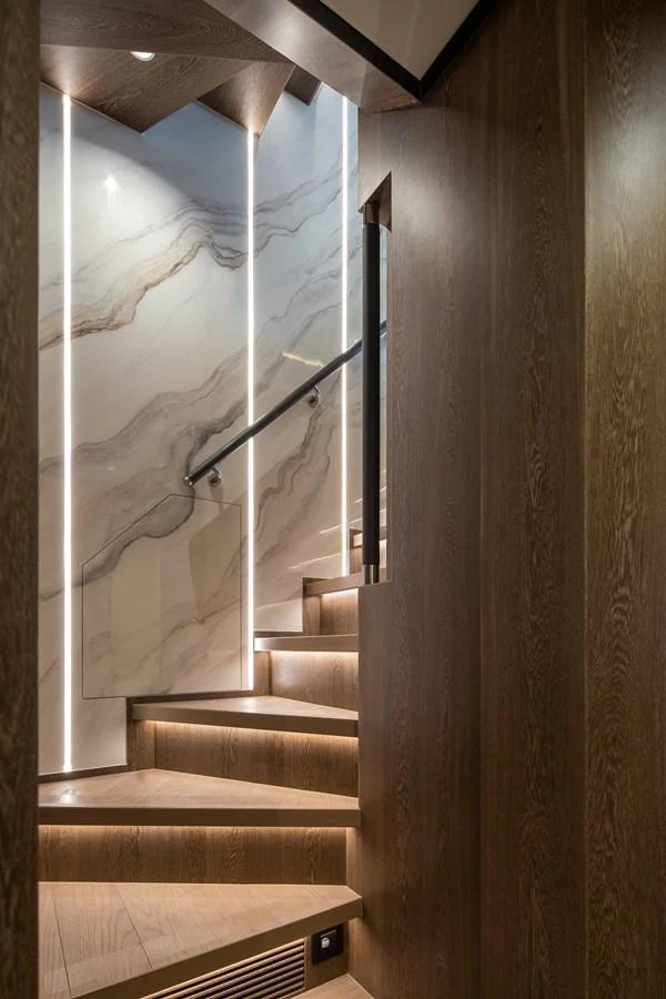 A beautifully designed staircase with elegant lighting and wood paneling. aboard HORIZON FD90 Yacht for Sale