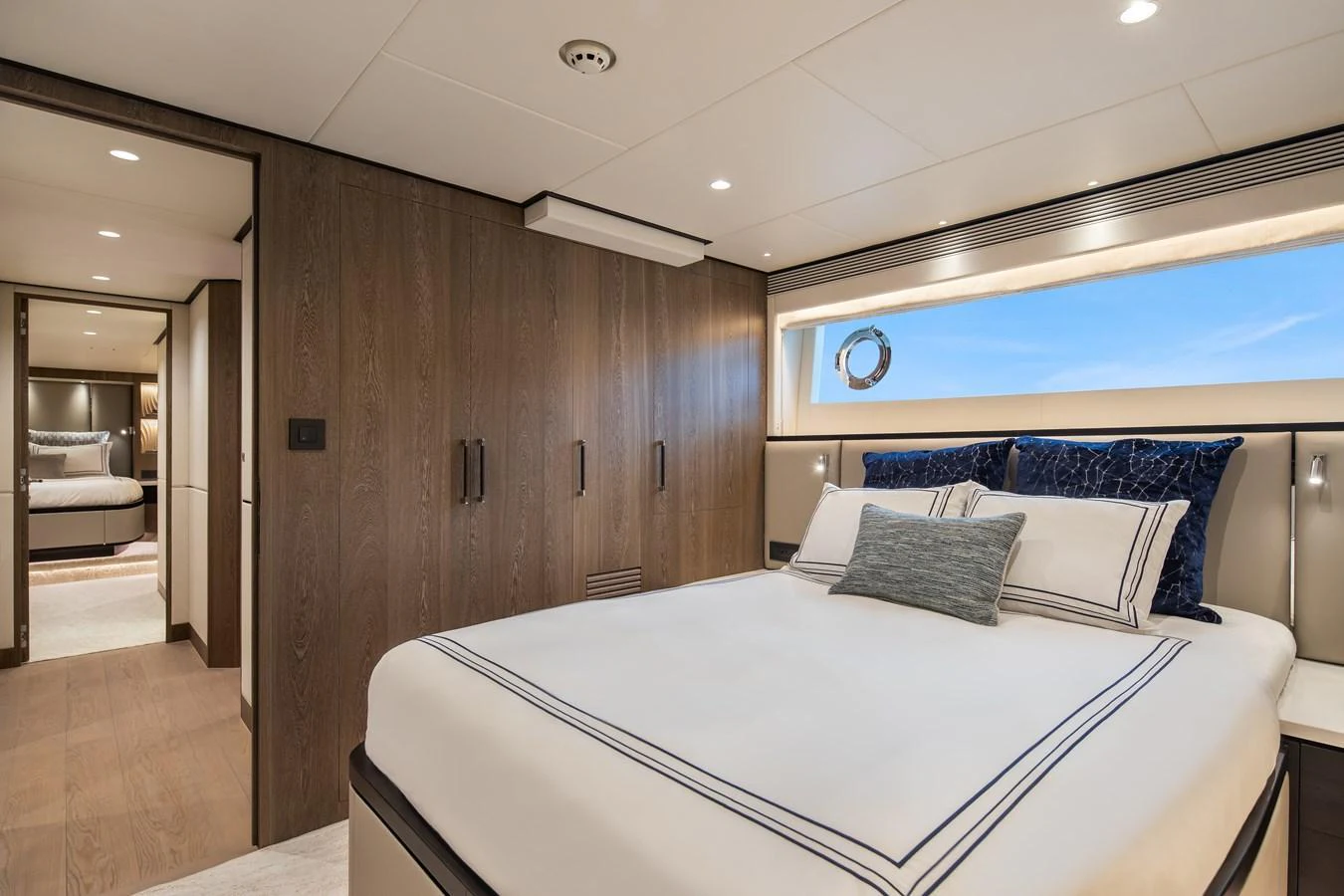 A luxurious guest stateroom featuring a comfortable bed, elegant wood paneling, and ample natural light. aboard HORIZON FD90 Yacht for Sale