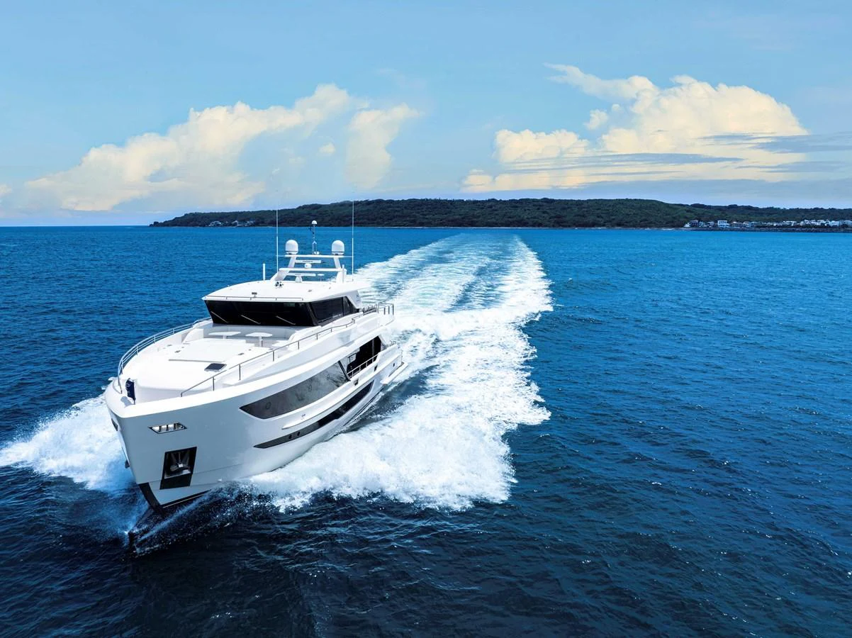 A sleek yacht cruises through the open sea, leaving a trail of white foam behind. aboard HORIZON FD90 Yacht for Sale