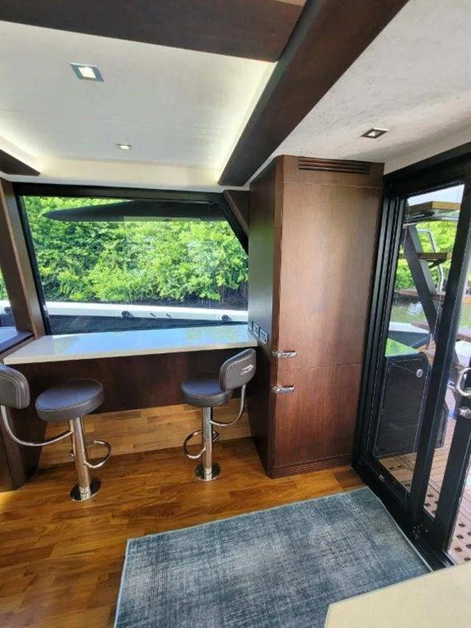The salon features a cozy seating area with bar stools and large windows offering a view of the outdoors. aboard GODSPEED Yacht for Sale