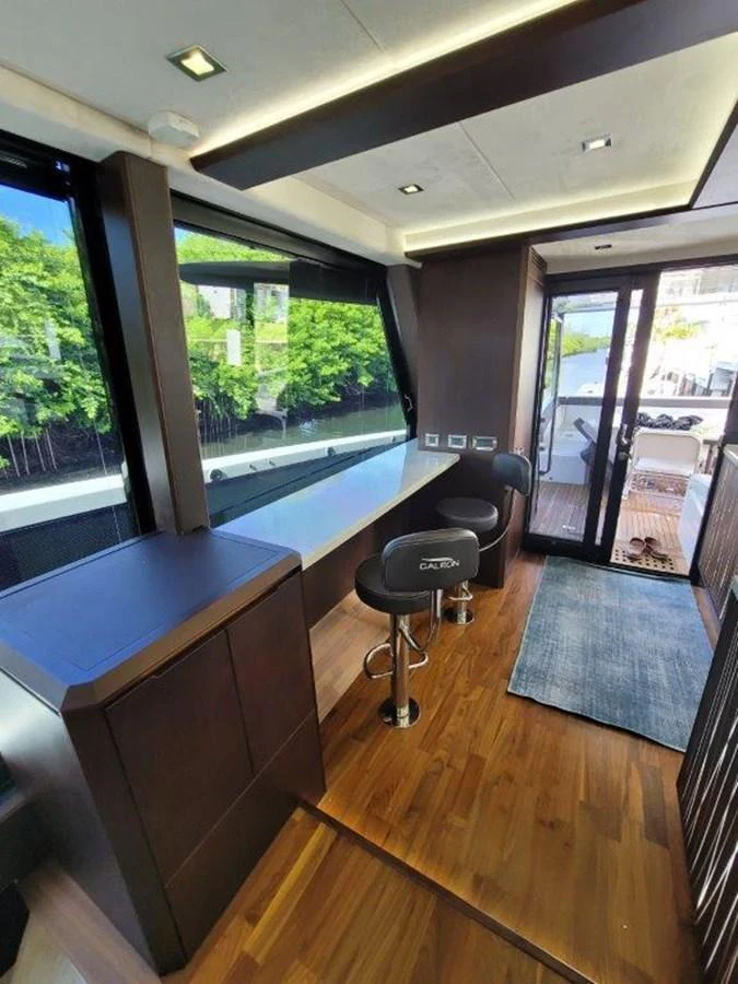 A sleek and modern interior space with bar stools and large windows offering a view outside. aboard GODSPEED Yacht for Sale