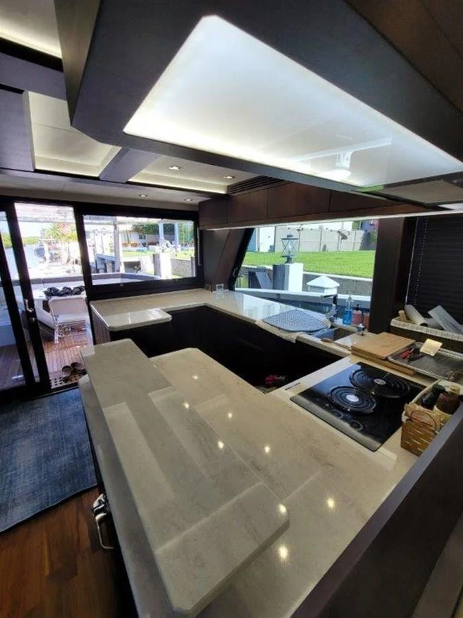 The modern galley features sleek countertops, a cooktop, and ample natural light. aboard GODSPEED Yacht for Sale