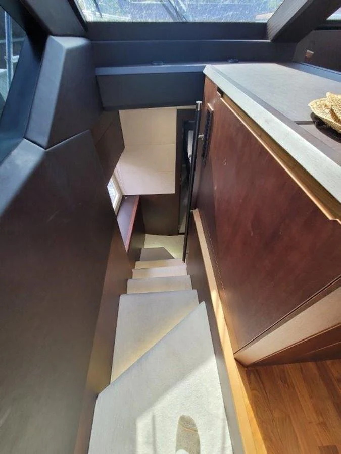 A well-lit staircase with wooden paneling and carpeted steps leads to the lower deck. aboard GODSPEED Yacht for Sale