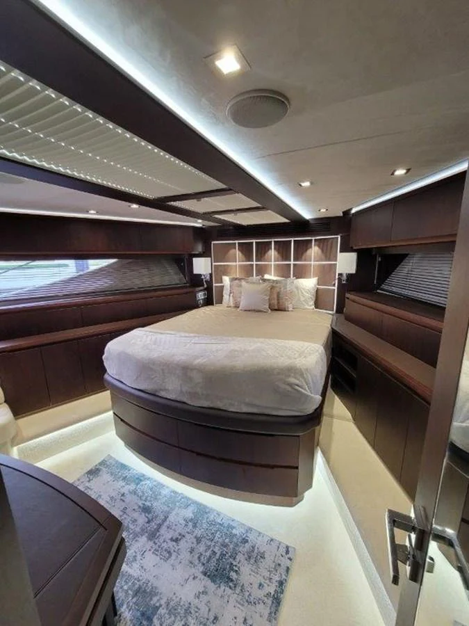 The stateroom features a luxurious bed with elegant wood paneling and ambient lighting. aboard GODSPEED Yacht for Sale