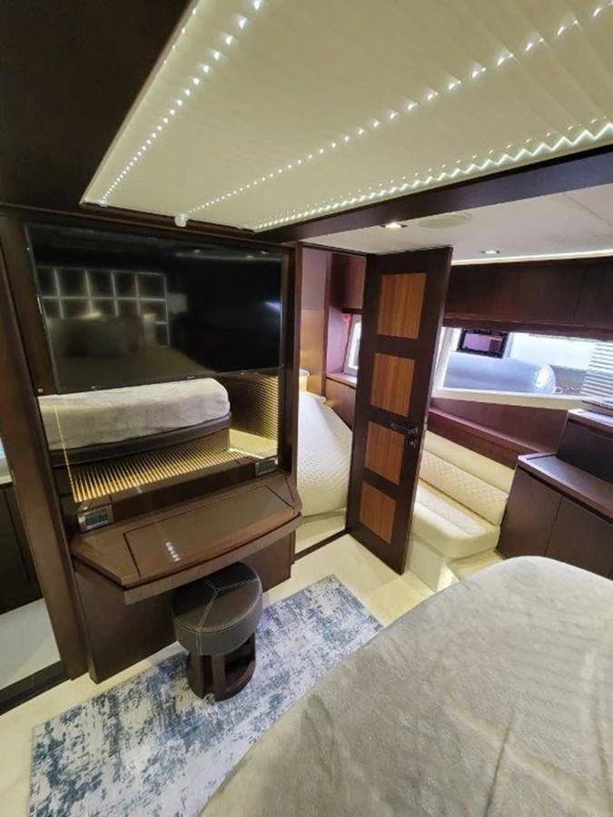 The stateroom features a cozy bed, a flat-screen TV, and elegant wood finishes. aboard GODSPEED Yacht for Sale