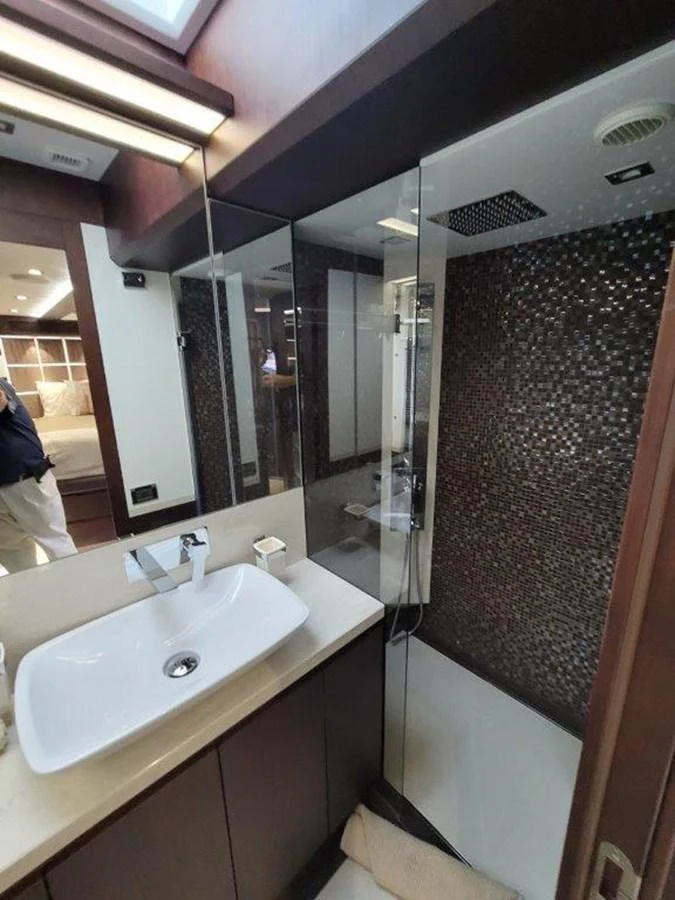 A sleek and modern yacht bathroom featuring a stylish sink and a glass-enclosed shower. aboard GODSPEED Yacht for Sale
