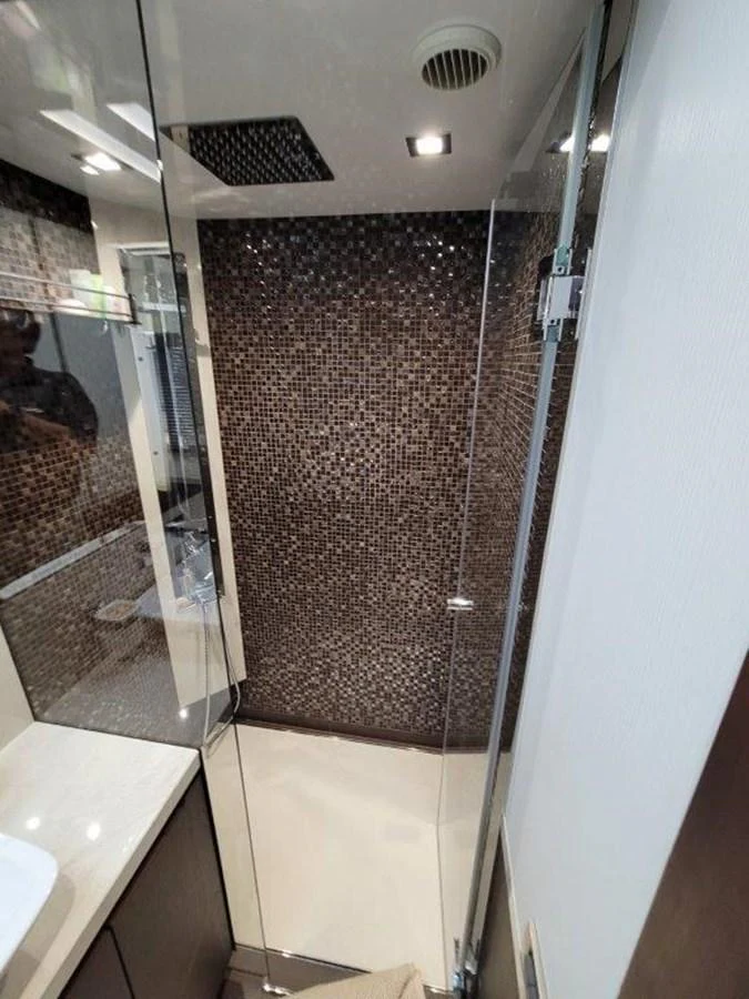 A modern yacht bathroom featuring a glass shower enclosure and mosaic tile wall. aboard GODSPEED Yacht for Sale