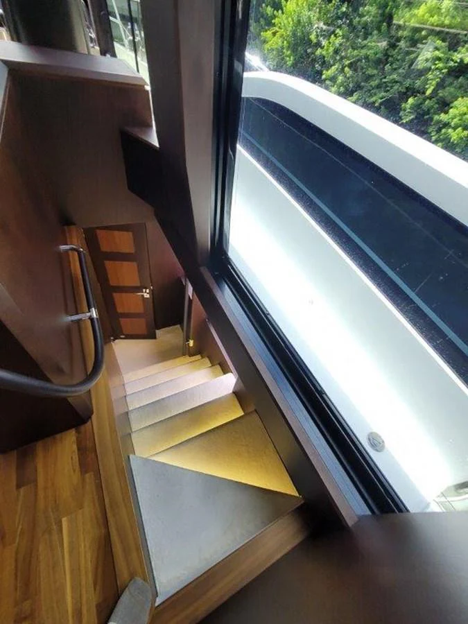 A sleek interior staircase with a large window offering a view of the outside. aboard GODSPEED Yacht for Sale