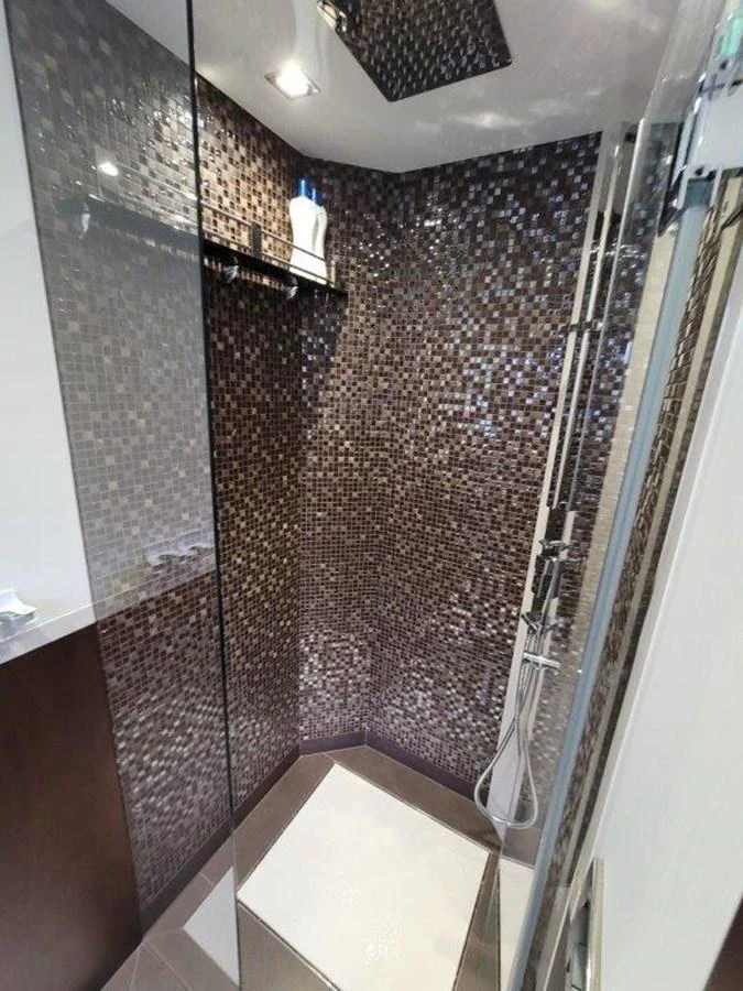 A modern shower area with elegant mosaic tiles and sleek fixtures. aboard GODSPEED Yacht for Sale