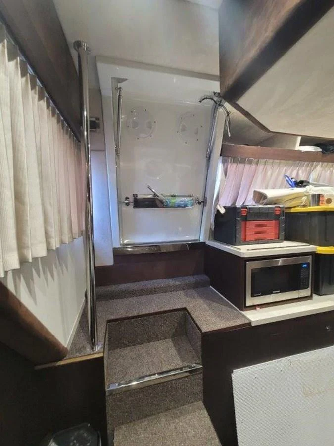 The image shows a compact interior space with stairs, a microwave, and storage areas. aboard GODSPEED Yacht for Sale