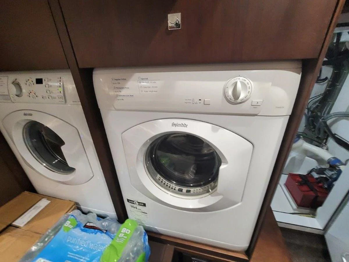 The image shows a compact laundry area with a washer and dryer on a yacht. aboard GODSPEED Yacht for Sale