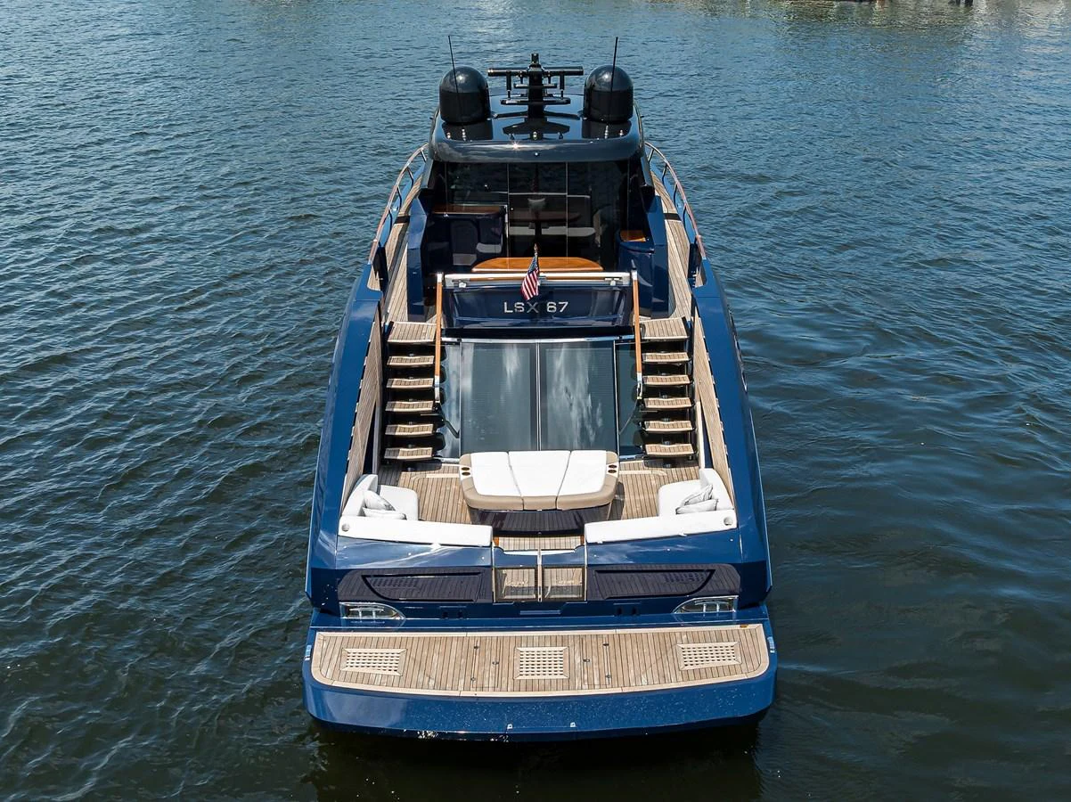 A sleek and modern yacht with a spacious aft deck and luxurious amenities is seen from the rear on calm waters. aboard LAZZARA LSX 67 Yacht for Sale
