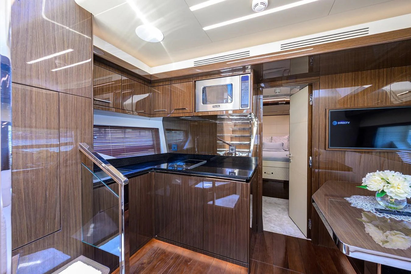 The yacht's galley features sleek wooden cabinetry, modern appliances, and a cozy dining area. aboard LAZZARA LSX 67 Yacht for Sale