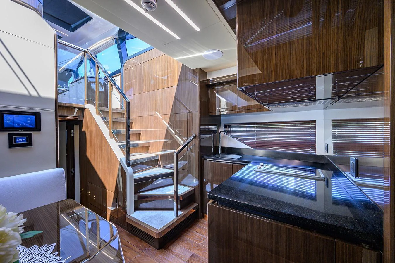 The yacht's galley features sleek wooden cabinetry and modern appliances, with a staircase leading to the upper deck. aboard LAZZARA LSX 67 Yacht for Sale