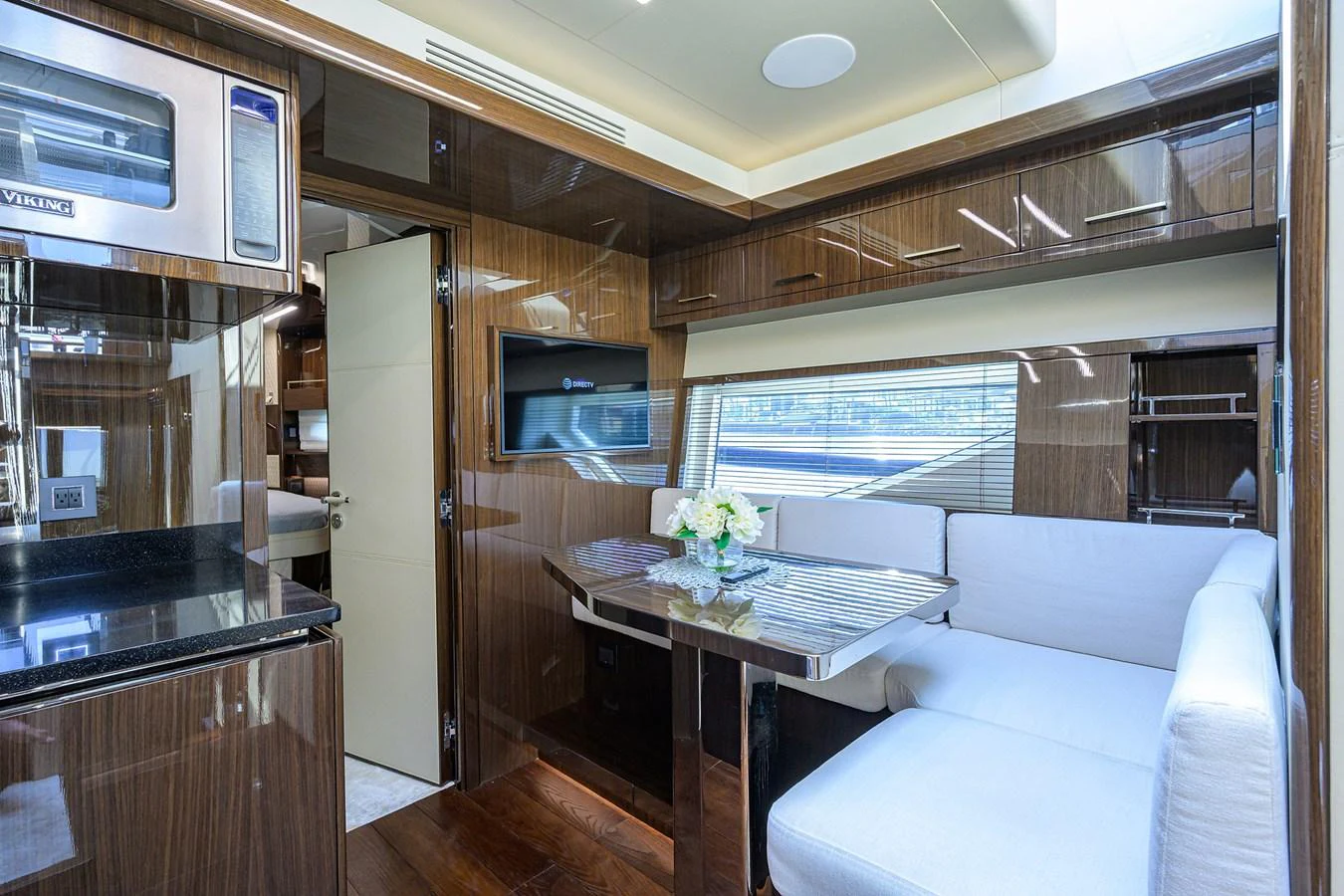 The salon features a cozy seating area with a table, accented by polished wood finishes and modern amenities. aboard LAZZARA LSX 67 Yacht for Sale