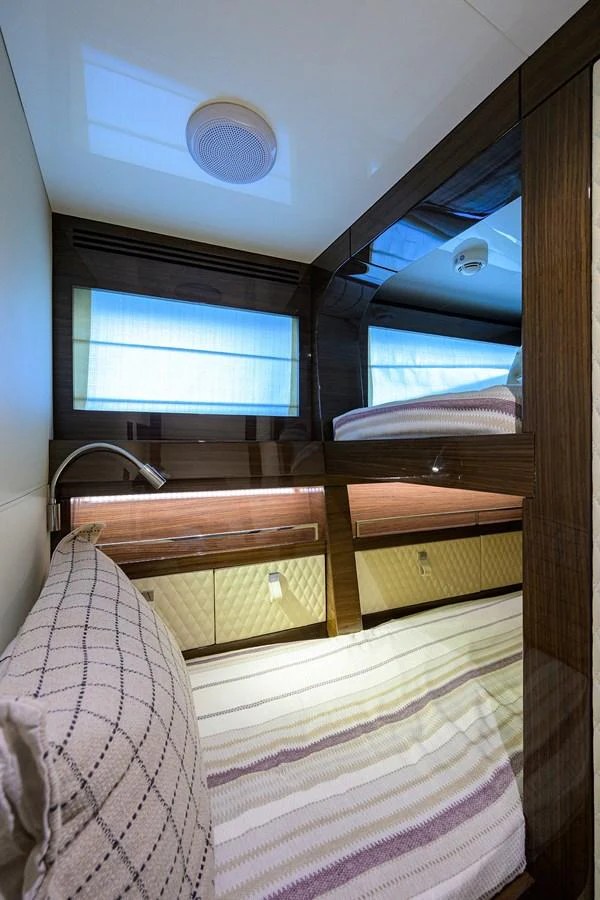 The guest cabin features a cozy bed with elegant wood finishes and ample natural light. aboard LAZZARA LSX 67 Yacht for Sale