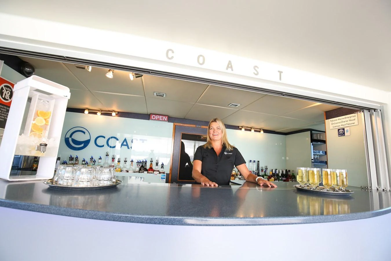 The yacht features a well-stocked bar with a friendly crew member ready to serve drinks. aboard COAST Yacht for Sale
