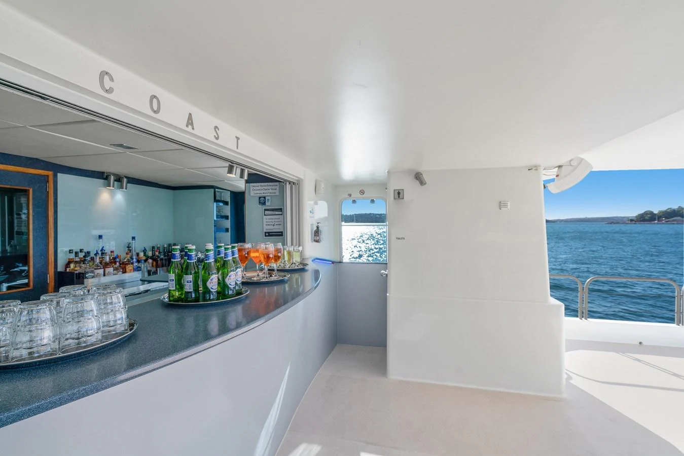 The yacht features a well-stocked bar area with a view of the water. aboard COAST Yacht for Sale