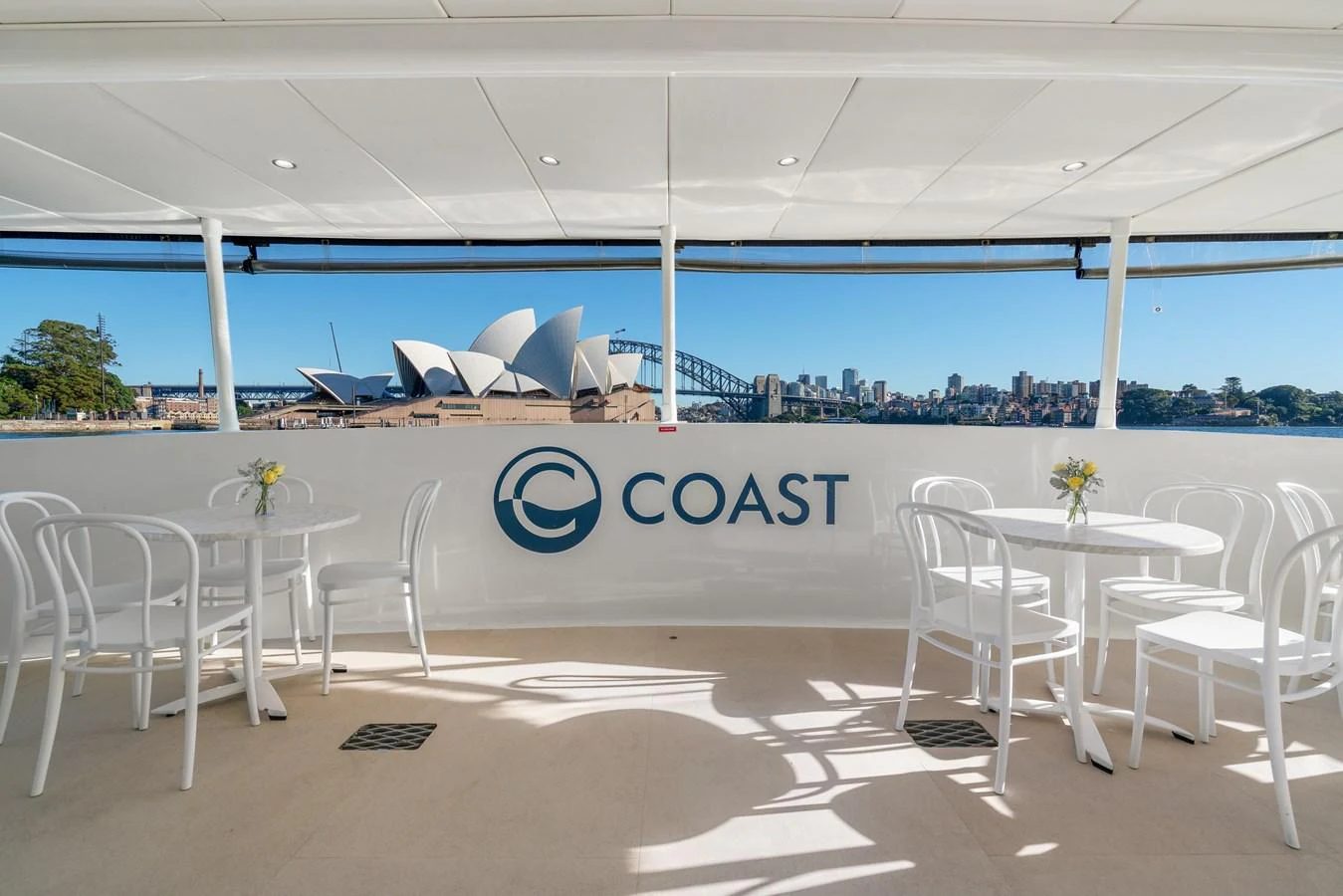 The aft deck offers a serene setting with white tables and chairs, perfect for enjoying scenic views. aboard COAST Yacht for Sale