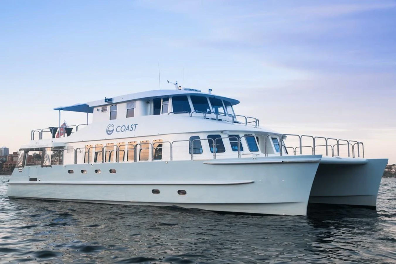 A sleek and modern catamaran yacht cruising on calm waters at sunset. aboard COAST Yacht for Sale