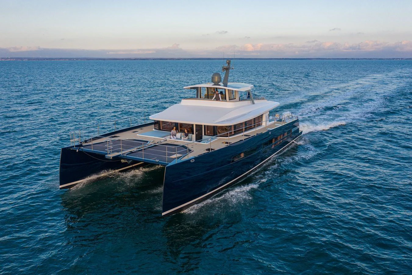 A sleek catamaran yacht glides effortlessly across calm waters, showcasing its modern design and spacious deck. aboard LONG ISLAND 78 Yacht for Sale