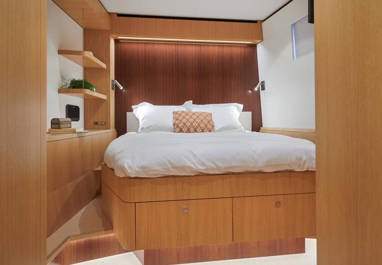 A cozy stateroom with a comfortable bed and modern wooden furnishings. aboard LONG ISLAND 78 Yacht for Sale