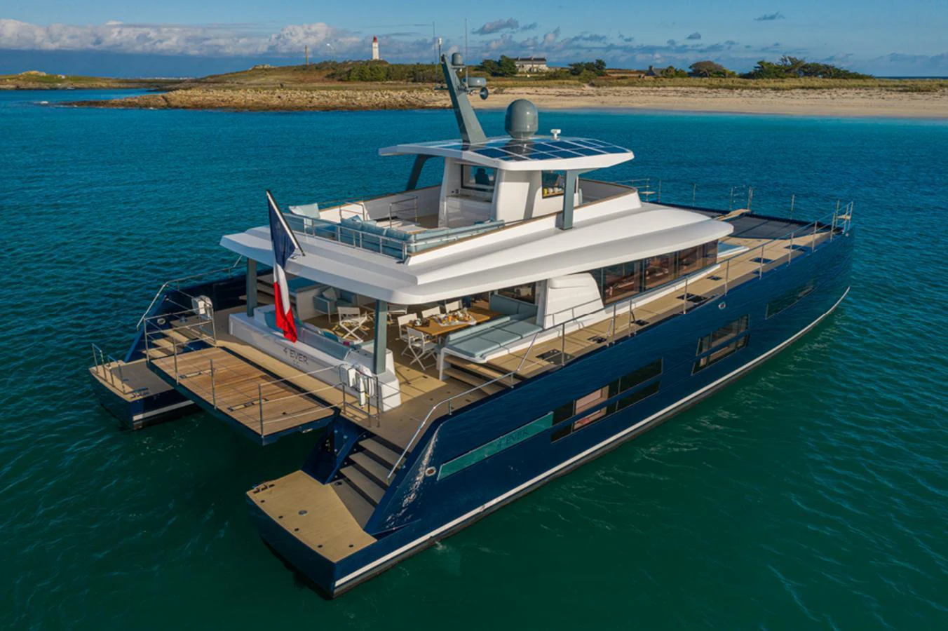 A sleek and modern yacht cruising in clear blue waters near a scenic coastline. aboard LONG ISLAND 78 Yacht for Sale