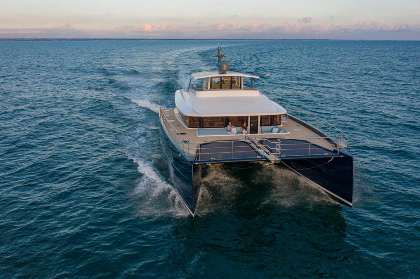 A sleek and modern yacht glides smoothly across the open water at sunset. aboard LONG ISLAND 78 Yacht for Sale
