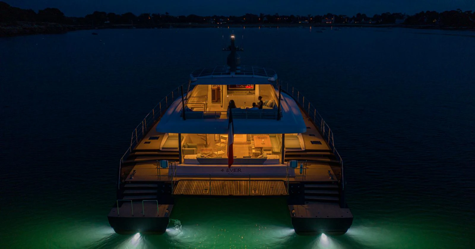 The yacht's aft deck is beautifully illuminated against the night backdrop, creating an inviting ambiance. aboard LONG ISLAND 78 Yacht for Sale