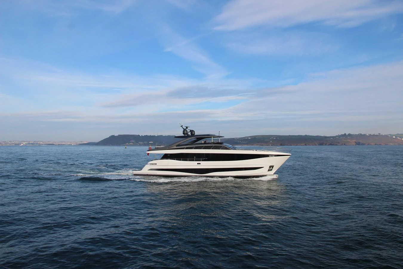 A sleek yacht cruises gracefully on calm waters under a clear sky. aboard LEILANI Yacht for Sale