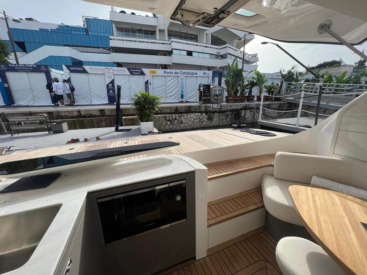 The aft deck features a cozy seating area with a wooden table and steps leading to the upper deck. aboard LEILANI Yacht for Sale