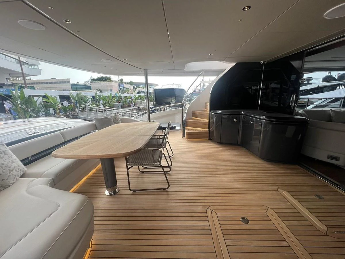 The aft deck features a spacious seating area with a dining table and elegant wooden flooring. aboard LEILANI Yacht for Sale