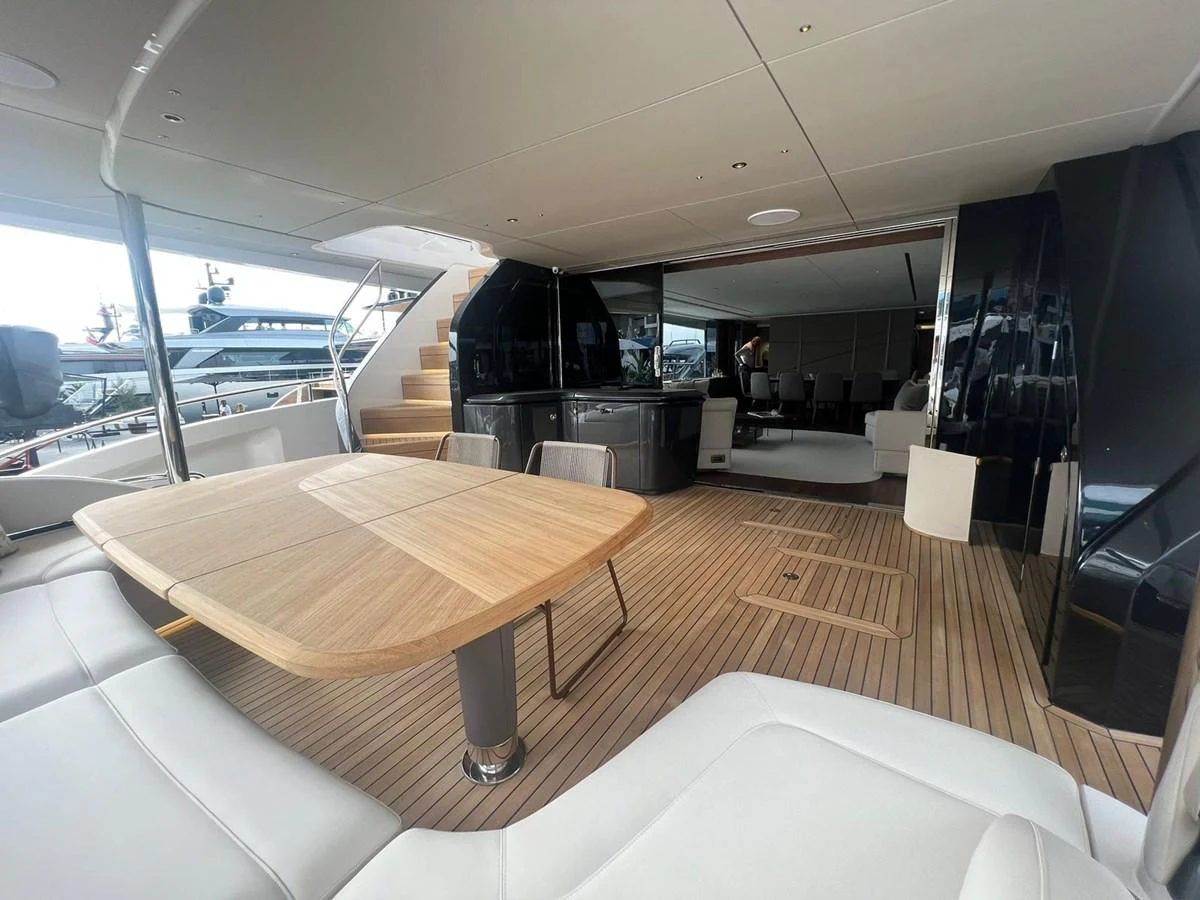 The aft deck features a spacious seating area with a wooden dining table and modern design elements. aboard LEILANI Yacht for Sale