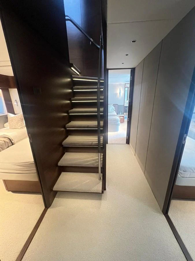 A well-lit interior hallway with a staircase leading to an upper deck. aboard LEILANI Yacht for Sale