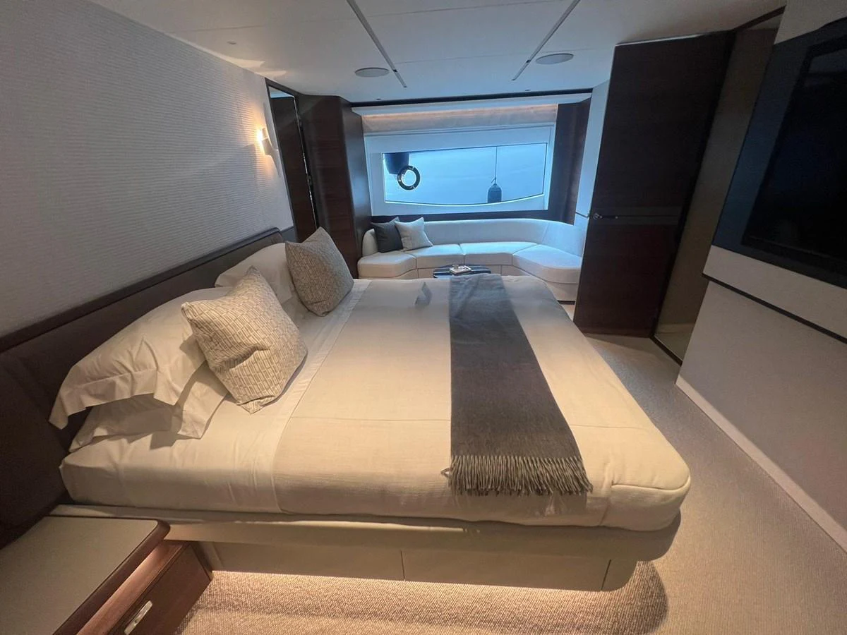 The stateroom features a luxurious bed with elegant bedding and a cozy seating area by the window. aboard LEILANI Yacht for Sale