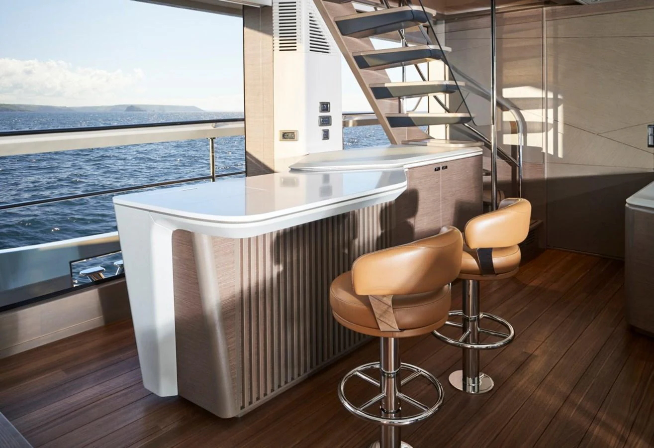 This stylish bar area features modern bar stools and a sleek countertop with a view of the sea. aboard OCEAN THREE Yacht for Sale