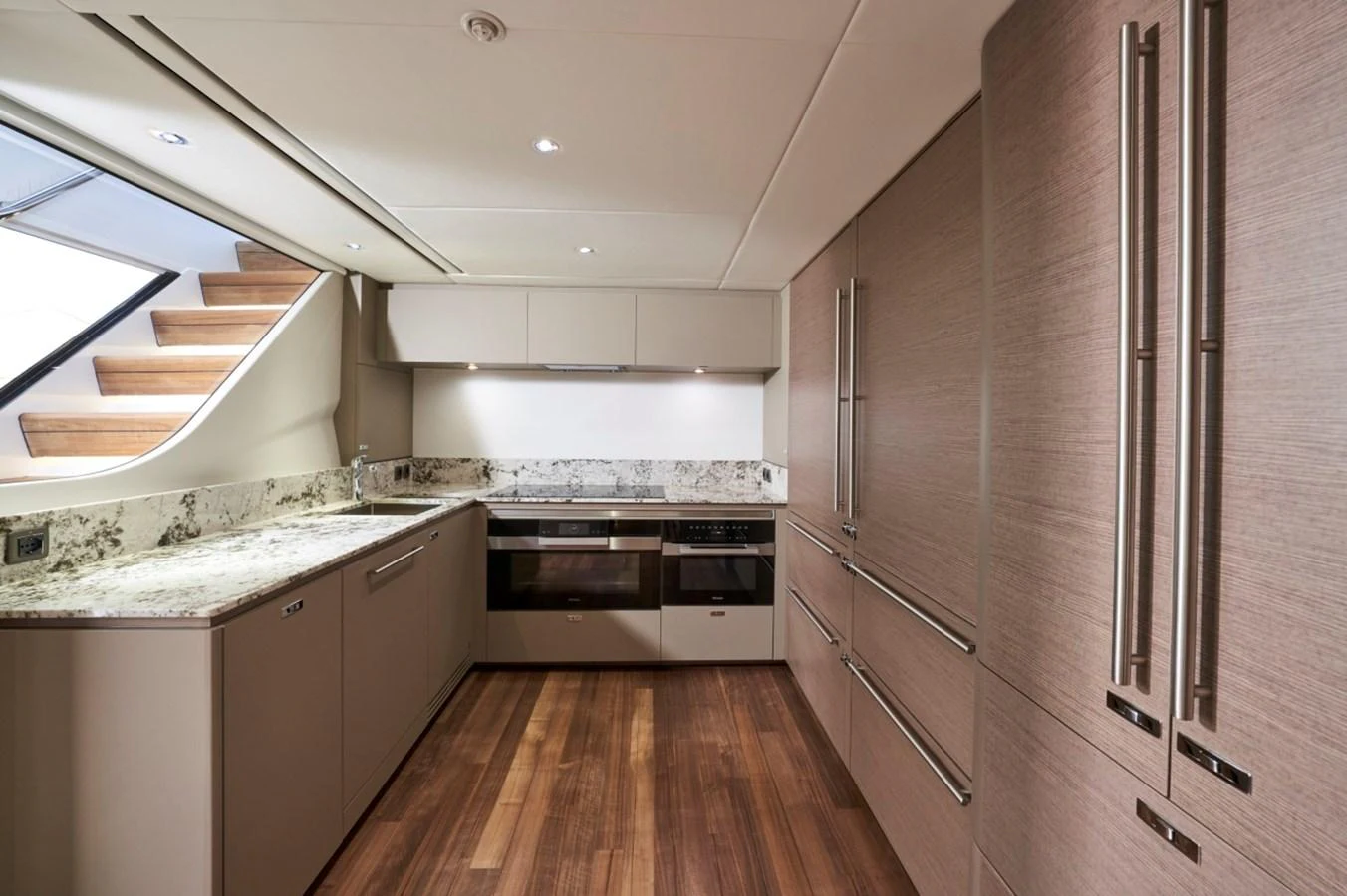 The yacht's galley features modern appliances, sleek cabinetry, and elegant wooden flooring. aboard OCEAN THREE Yacht for Sale