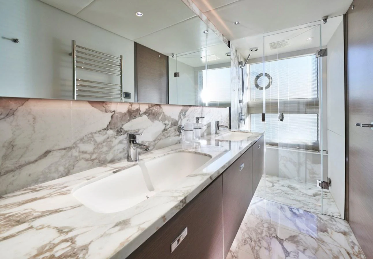 The yacht's bathroom features luxurious marble countertops and a spacious glass-enclosed shower. aboard OCEAN THREE Yacht for Sale