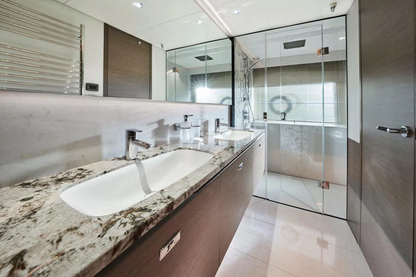 The yacht's bathroom features a luxurious double sink vanity with a spacious glass-enclosed shower. aboard OCEAN THREE Yacht for Sale